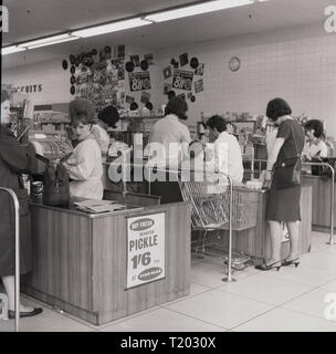 Années 1960, historiques, femme au shoppers caisses à un nouveau tarif 'Belle' supermarché, England, UK. Bien que les supermarchés ont été lentes à décoller dans le Royaume-Uni, à la fin du rationnement a vu augmenter la consommation personnelle et bien qu'il n'avait que 50 ou alors en existence au début des années 50, à la fin de la décennie, plus de 500 ont ouvert, y compris le Premier Ministre, et tarif Fiine Victor Valeur. Banque D'Images