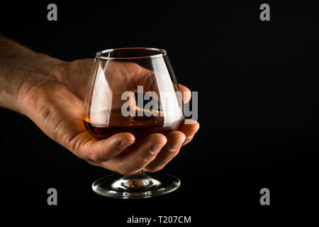 Tenir l'homme de verre de cognac ou de brandy à la main. Banque D'Images