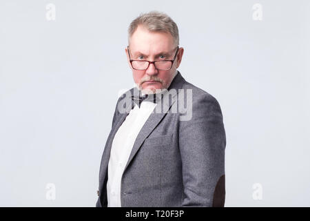 Vieil homme en costume et lunettes looking at camera avec confiance. Shoot Studio. Banque D'Images