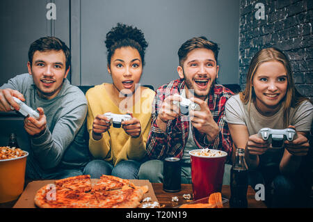 Close up de quatre amis assis ensemble et jouer le jeu. Tous veulent gagner. Ils jouent très intenses. Ils ne sont d'ailleurs profiter de la t Banque D'Images