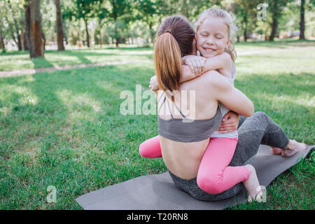 Une autre photo de happy child hugging her parent. Elle est assise sur sa mère avec les yeux fermés. Elle déguste le moment. Yoga et Pilates Concep Banque D'Images