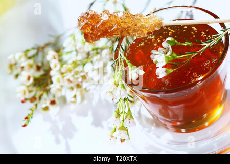 Miel de fleurs joliment décorées dans un verre. Sur le dessus il y a un sucre candy stick. Banque D'Images