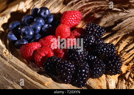 Divers petits fruits disposés sur un bois décoratif. Banque D'Images