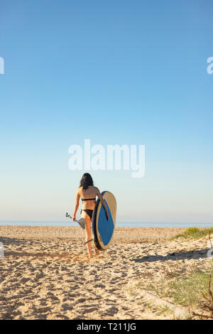 Espagne, Andalousie, Tarifa, woman walking with stand up paddle board sur la plage Banque D'Images