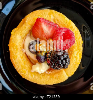 Mini gâteau décoré avec des fraises fraîches, de framboise, de mûre, de la poussière d'or, et l'été des petits fruits sur une plaque noire. Belle pâtisserie, petite c Banque D'Images