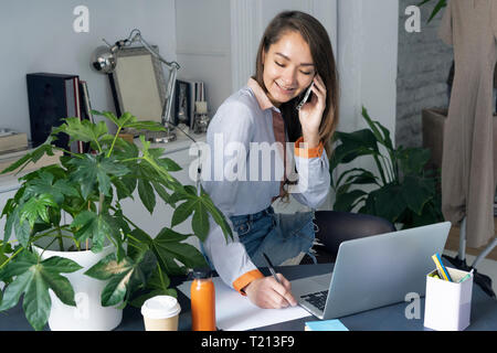 Young businesswoman working from home, parler au téléphone Banque D'Images