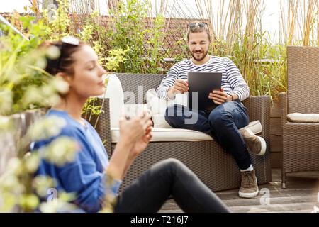 Couple sur leur balcon, man sitting on couch, using laptop Banque D'Images