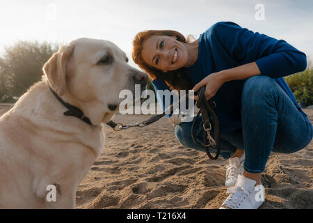Allemagne, Hambourg, smiling woman with dog on beach au bord de l'Elbe Banque D'Images