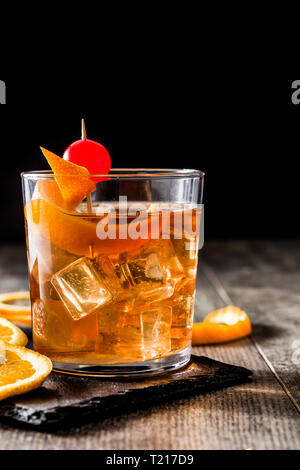 Cocktail à l'ancienne avec orange et cerise sur table en bois Banque D'Images