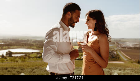 Close up of a romantic couple standing proches l'un de l'autre tenant un verre de vin. Couple heureux de passer du temps ensemble sur une date. Banque D'Images
