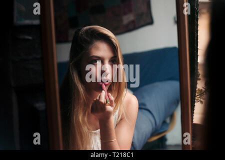 Image miroir de young woman applying lipstick Banque D'Images