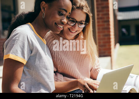 Deux jeunes recherche d'informations pour leur étude sur l'ordinateur portable au collège. Les jeunes étudiants assis à l'université campus working on laptop comput Banque D'Images