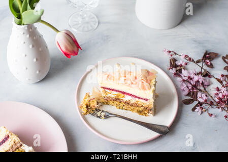 Une tranche de mousse au chocolat sur une assiette blanche et d'une tulipe fleur dans un vase blanc Banque D'Images