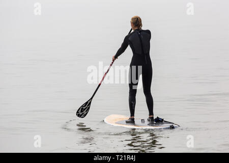 Branksome déné, Poole, Dorset, UK. 30Th Mar, 2019. Météo France : hazy sunshine matin et le refroidisseur de la fin, mais n'empêche pas les visiteurs de se diriger vers la mer à la Branksome dénés. Femme paddleboarding standup paddle standup paddleboarder. crédit : boarder Carolyn Jenkins/Alamy Live News Banque D'Images