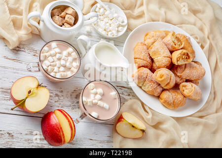 Apple Pie mini croissants d'une bouchée, kifli, rohalik servi sur une plaque blanche avec du chocolat chaud arrosé avec de la guimauve dans cups sur une table en bois blanc, v Banque D'Images