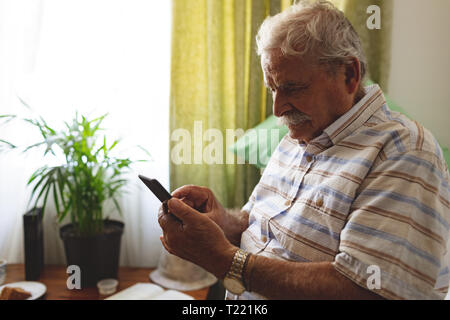 Senior téléphone mobile à la maison de soins infirmiers Banque D'Images