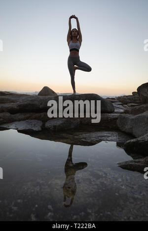 Woman doing yoga on rock at beach Banque D'Images