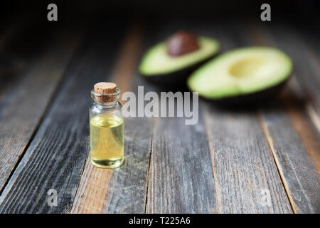 Petite bouteille de l'huile d'avocat et les avocats sur table en bois Banque D'Images