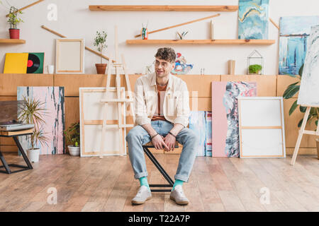 Handsome smiling artiste assis sur une chaise dans une chambre spacieuse galerie lumière Banque D'Images