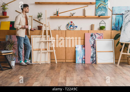 Artiste beau standing spacieux studio de peinture de lumière et la tenue de tasse de café Banque D'Images