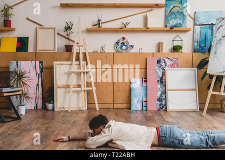 Pose de l'artiste face vers le bas sur le plancher en bois dans un grand studio de peinture Banque D'Images