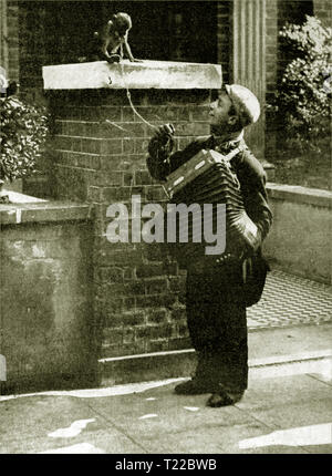 Années 1930, un orgue de Barbarie (artiste de rue) avec son singe sur une rue de Londres transportant son accordéon Banque D'Images