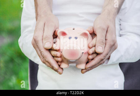 L'enfant et les parents sont holding a piggy bank dans leurs mains. la nature. Banque D'Images