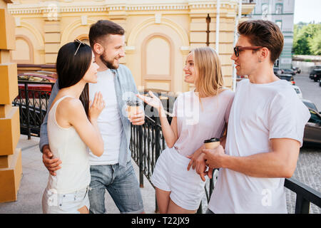 Les filles et les garçons sont debout deux par deux en face de l'autre. Fille blonde parle de barbu. Barbu adopte chinese girl Banque D'Images