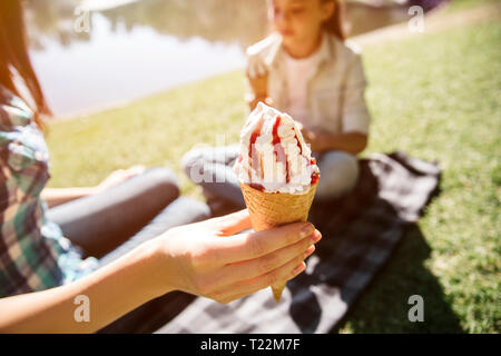 Belle photo de la stabulation des adultes con de glace dans la main. Il y a une fille assise en plus des profils et la tenue de trop icream con Banque D'Images