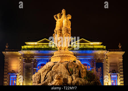 Vue sur la statue des Trois Grâces dans la nuit avec un opéra sur l'arrière-plan dans la ville de Montpellier en France Banque D'Images