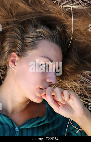 Portrait of young woman lying on straw Banque D'Images