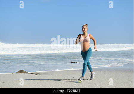 Smiling pregnant woman jogging sur la plage Banque D'Images