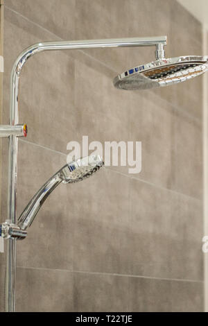 Pomme de douche Chrome et rampe sur carreaux gris. Banque D'Images