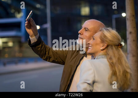 Espagne, Barcelone, happy senior couple prendre un en selfies la ville au crépuscule Banque D'Images