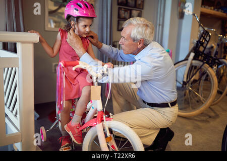 Heureux grands-parents d'acheter de nouveaux vélos et casques pour enfant fille Banque D'Images