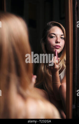 Image miroir de young woman applying lipstick Banque D'Images
