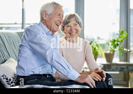 Portrait of laughing senior couple sitting on couch Banque D'Images