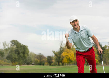 L'approche du golfeur satisfait après avoir réussi le trou mettre shot. Banque D'Images