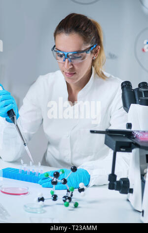 Chercheur en sciences femelle à l'aide de micropipettes en laboratoire. Banque D'Images