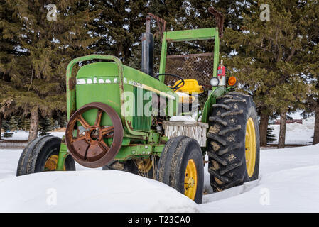 Vintage tracteur vert et jaune dans une neige en Saskatchewan, Canada Banque D'Images