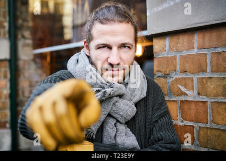 Portrait de jeune homme barbu portant des gants et écharpe pointant sur viewer Banque D'Images