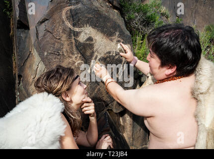 Grotte des gens habillés en peau d'animaux près de l'ancienne grotte dessin dans les rochers Banque D'Images