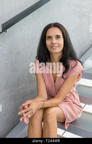 Portrait of smiling mature woman sitting on stairs Banque D'Images