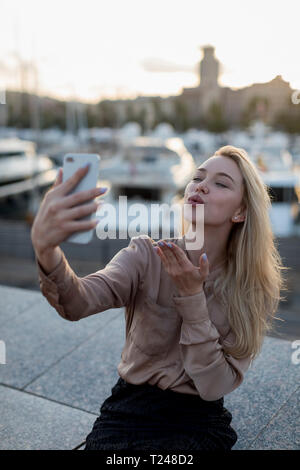 Jeune femme tenant un soufflage selfies et un baiser sur le front de mer Banque D'Images