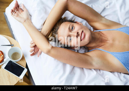 Portrait of smiling young woman Lying in Bed Banque D'Images