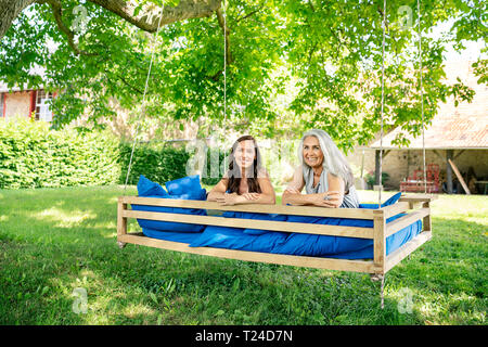 Portrait de deux couple de détente sur un lit suspendu dans le jardin Banque D'Images