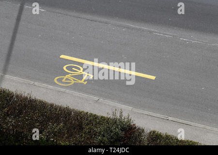 Yellow Bike Lane marqués d'un vélo peint signe. Il y a aussi, de l'allée de la rue et de l'herbe dans cette photo. Photographié à partir de ci-dessus. Banque D'Images