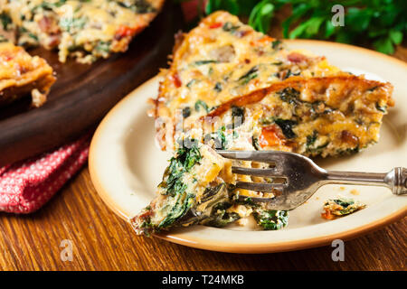 Partie de la frittata faite d'oeufs, les champignons et les épinards sur une assiette. La cuisine Italienne Banque D'Images