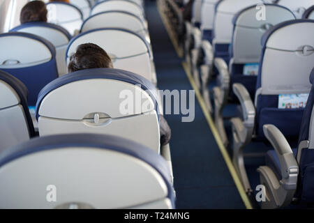 Avion à moitié vide avec peu de passagers. Passagers à l'intérieur de la cabine d'un avion en vol. Banque D'Images