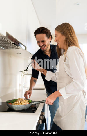 Couple heureux la préparation de spaghetti dans leur cuisine Banque D'Images